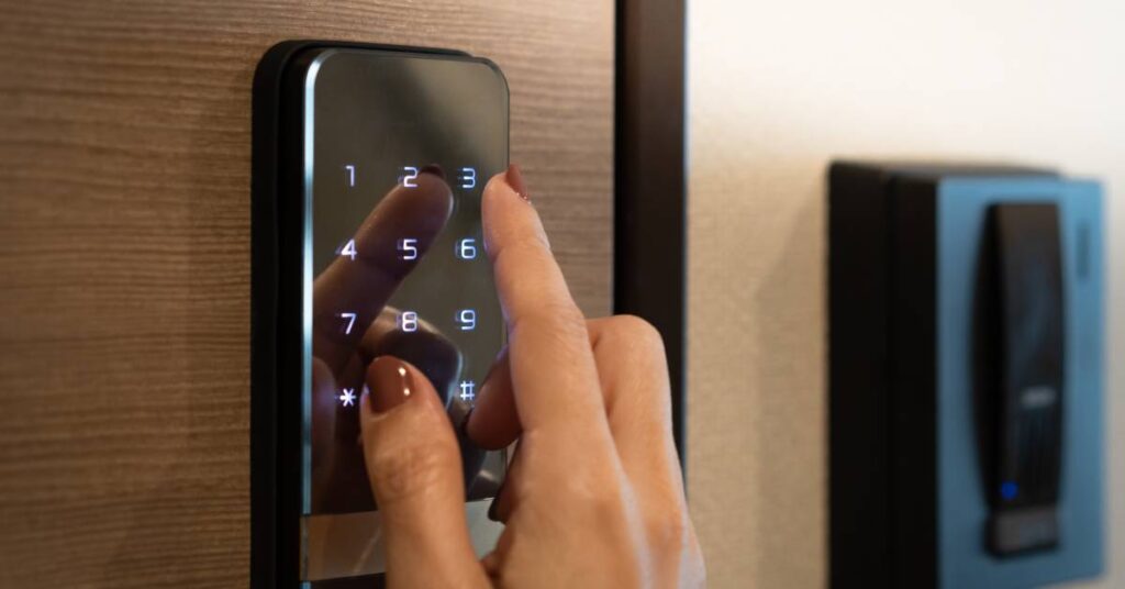 A close-up of a woman's hand with brown nail polish on her nails, pointing her finger to tap on a touch screen keypad